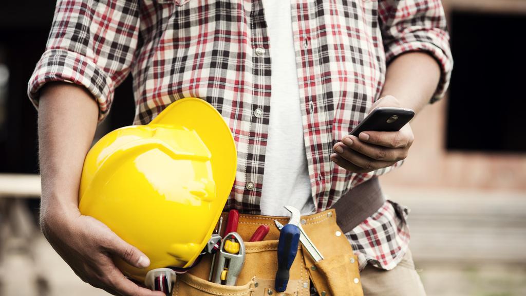 Construction worker typing on a smartphone