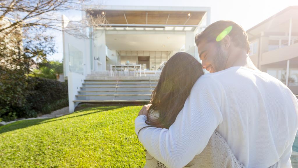 Young Couple standing in front of a modern new house.