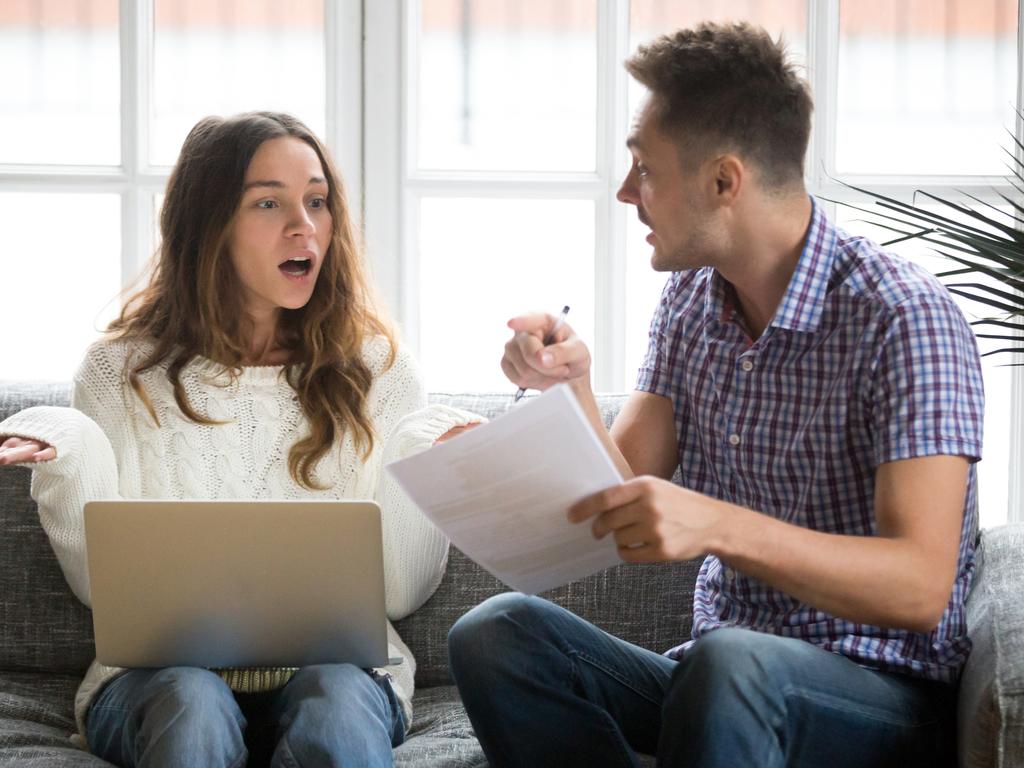 Worried couple arguing about debt bills with laptop and documents