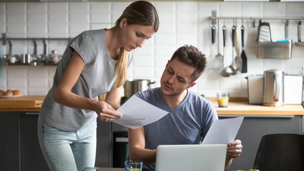 Serious young couple worried discussing utility bills in the kitchen