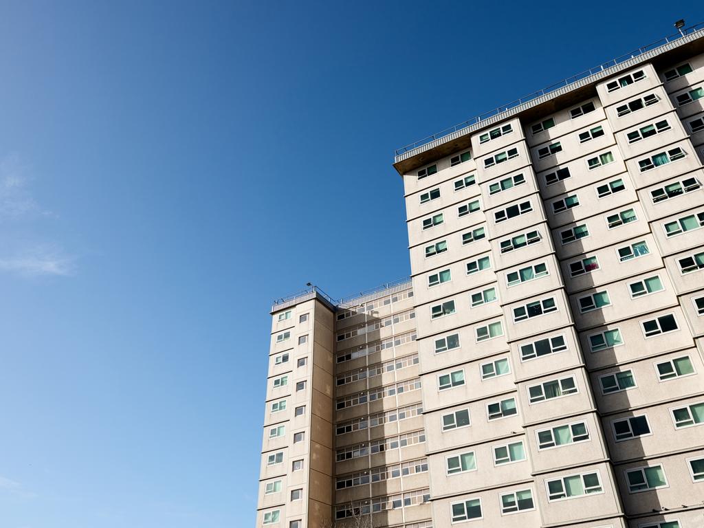 Social housing apartment tower block against a blue sky.