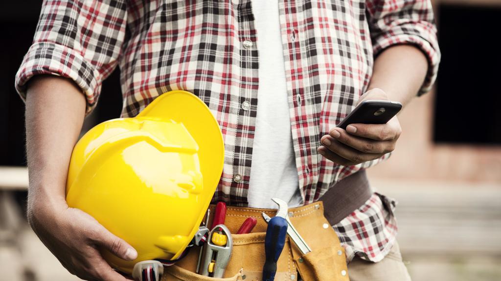 Construction worker typing on a smartphone