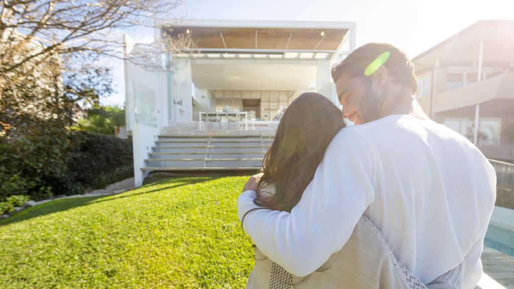 Young Couple standing in front of a modern new house.