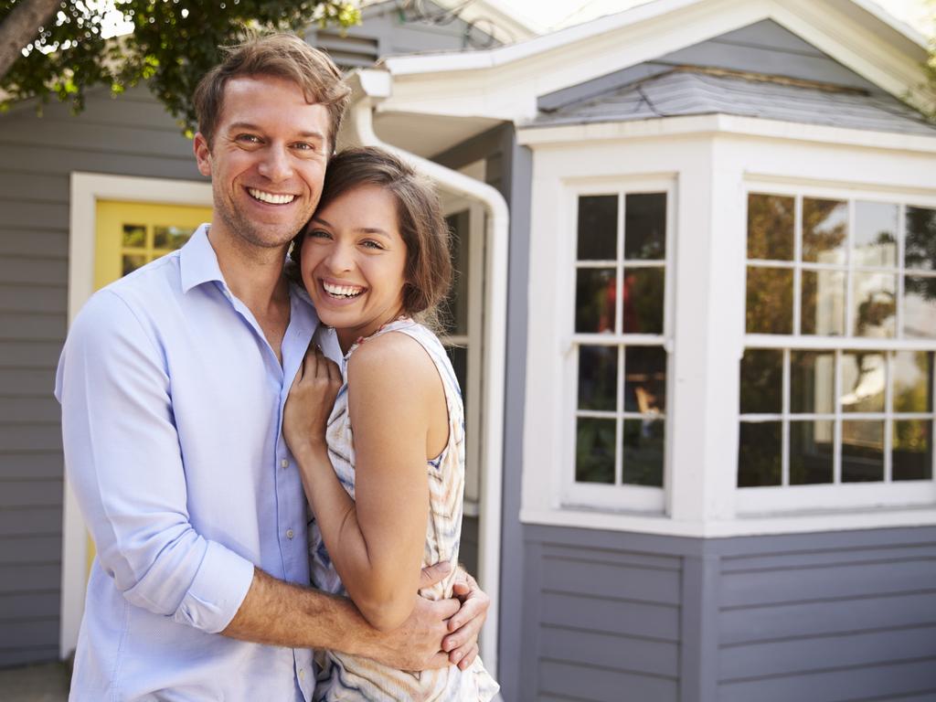 Portrait Of Excited Couple Standing Outside New Home