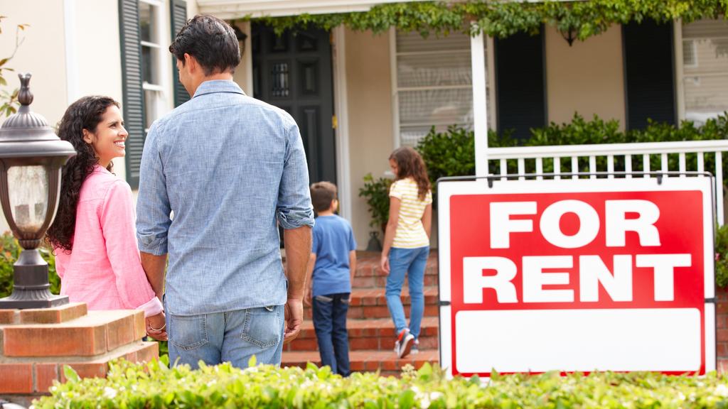 Smiling Hispanic family outside rental home