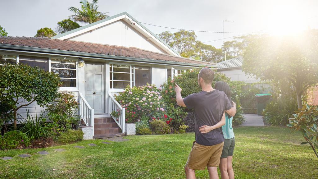 Happy mixed-race couple standing in front of house