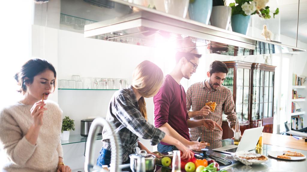 group of friends eating on the kitchen and preparing food