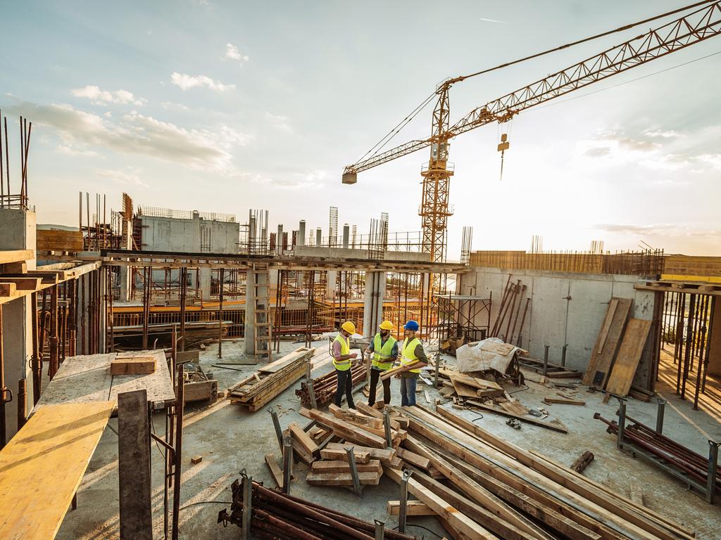 Construction site with three engineers and crane on the top of new skyscraper