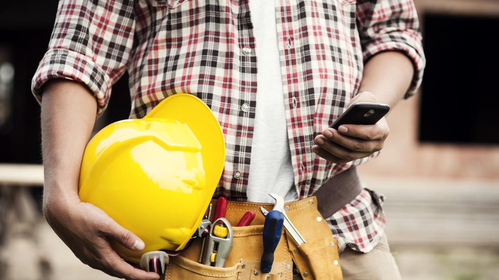 Construction worker typing on a smartphone