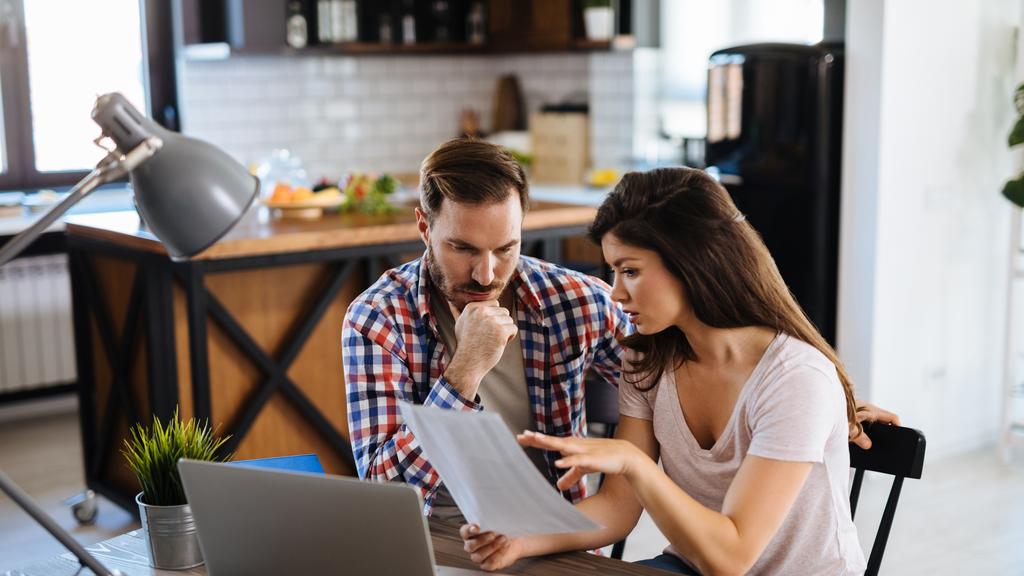 Frustrated couple checking bills at home using laptop