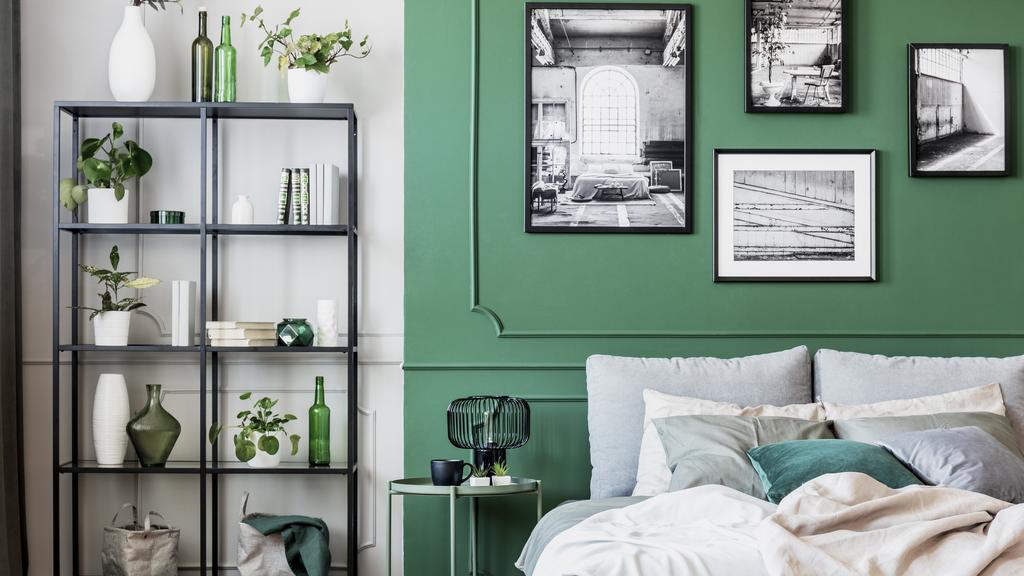 Gallery of black and white poster on green wall behind king size bed with pillows and blanket