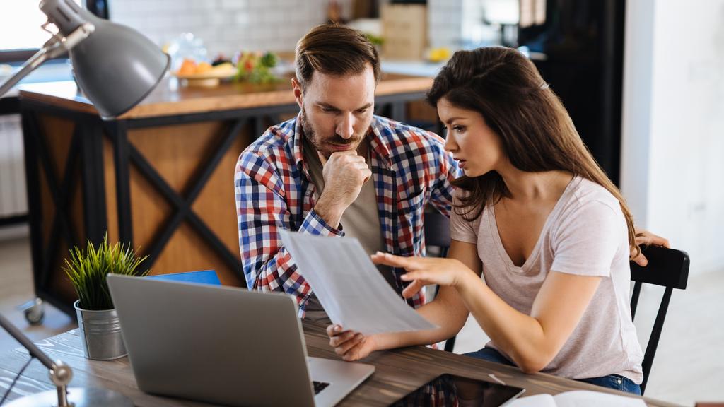 Frustrated couple checking bills at home using laptop